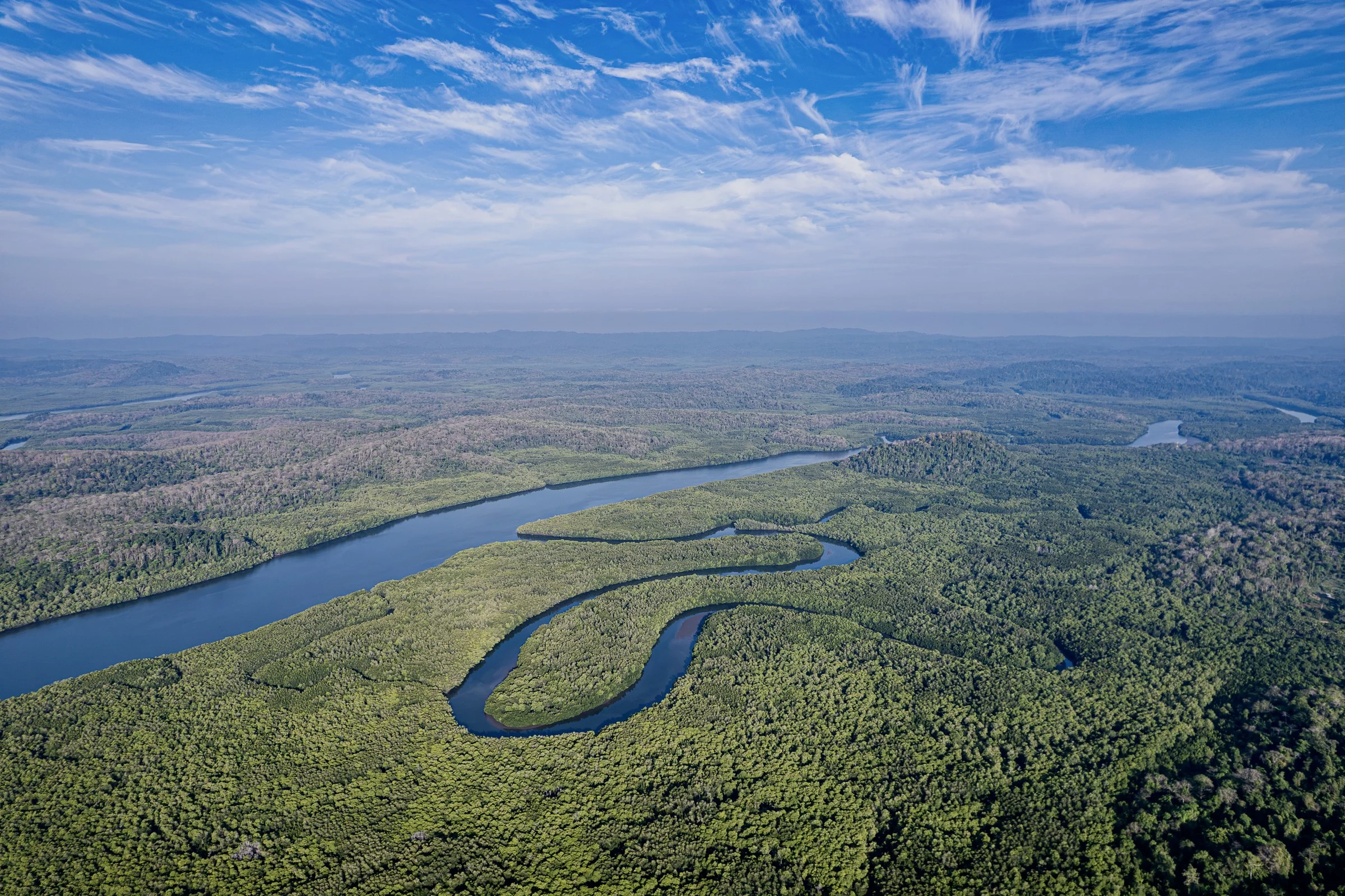 An aerial landscape of winding waterways beneath a wide blue sky