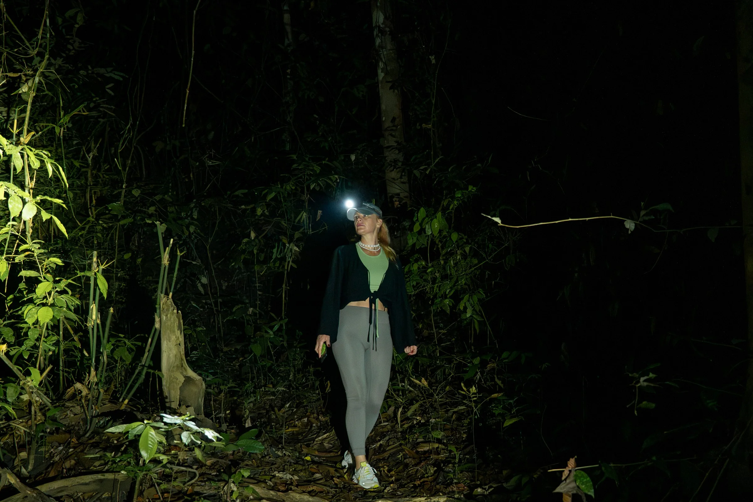 A person with a headlamp on a forest trail at night
